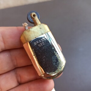 May include: A vintage brass lighter with a silver finish. The lighter has a wick and a flint wheel. The lighter is engraved with the words "BRASS N95".