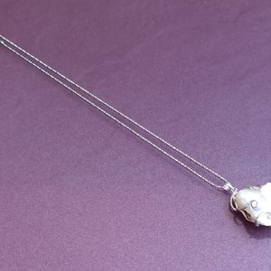 May include: A silver chain necklace with a white pearl pendant wrapped in silver wire.