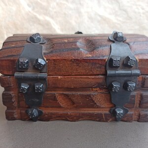 May include: A small wooden treasure chest with black metal hinges and decorative studs. The chest has a rustic, antique look.