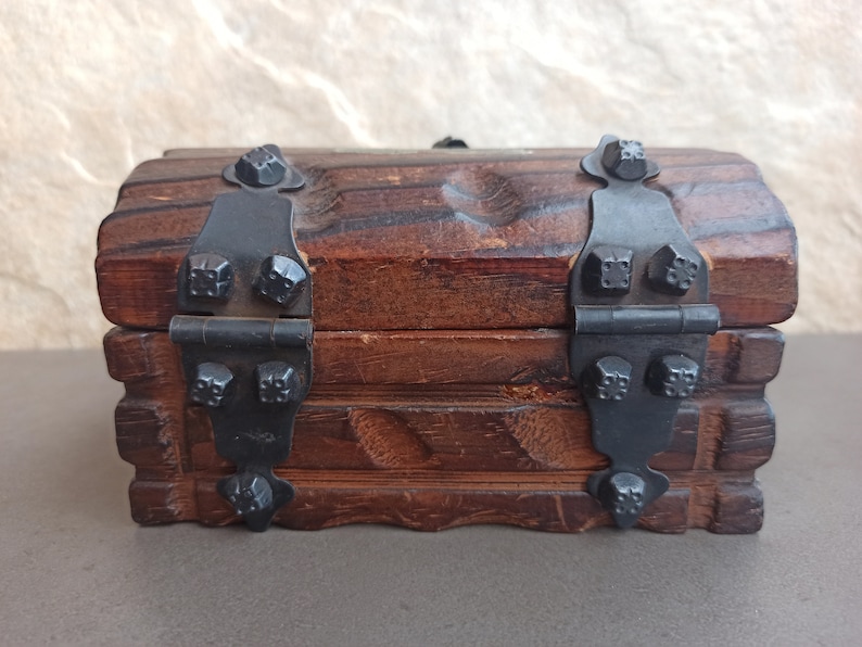 May include: A small wooden treasure chest with black metal hinges and decorative studs. The chest has a rustic, antique look.