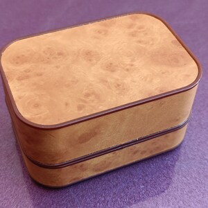 Op de afbeelding: Een houten doos met twee verdiepingen met een bruin houtnerfpatroon en een donkerbruine rand. De doos is gesloten.