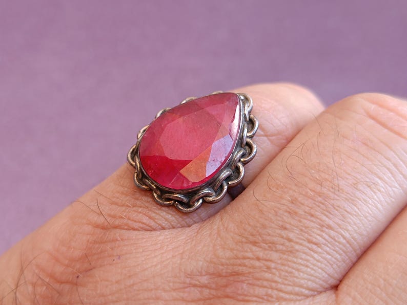 Pode incluir: Um anel de prata com uma grande pedra vermelha em forma de l&aacute;grima.