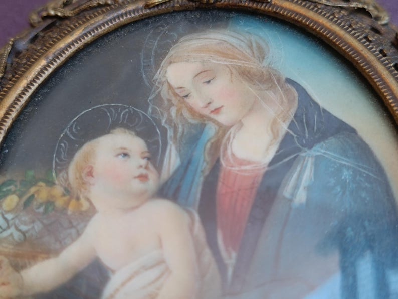 K&ouml;nnte beinhalten: Ovales antikes Portr&auml;t der Jungfrau Maria und des Jesuskindes, gerahmt in Goldfiligran. Das Kunstwerk zeigt weiche Pastellfarben, mit der Jungfrau Maria in einem blauen Umhang und dem Jesuskind mit Heiligenschein. Ein klassisches religi&ouml;ses Kunstwerk.