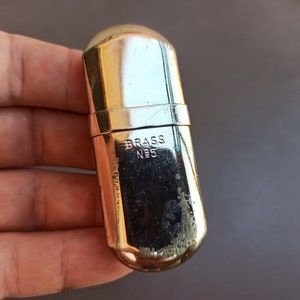 May include: A silver-colored metal lighter with the words "BRASS N95" engraved on the side.