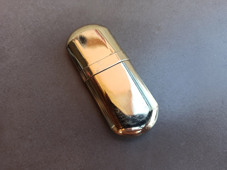 May include: A silver metal lighter case with a rounded shape.