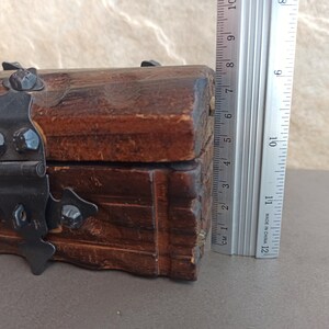May include: A wooden box with a hinged lid and a metal latch. The box is decorated with carved details and has a dark brown finish.