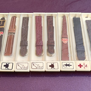 May include: Ten different watch bands in individual clear plastic boxes. Each box has a different animal graphic on the front. The watch bands are made of leather and have a variety of colors and patterns.