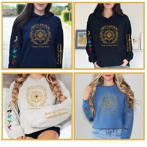 May include: Four different color sweatshirts with a gold design on the front that says "ONYX STORM" and a gold design on the sleeves. The design on the front includes a circle with a star inside and a wreath around it. The design on the sleeves includes a sword and four dragons in different colors.