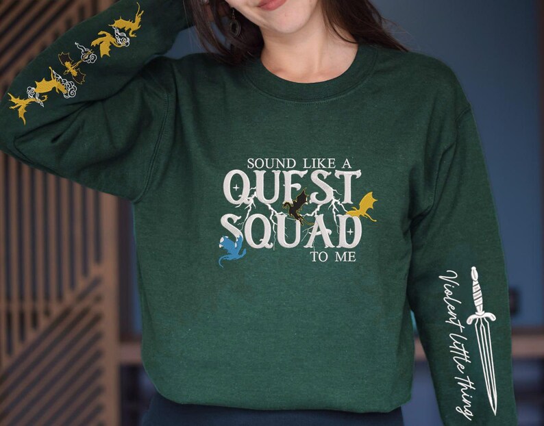 May include: Green long-sleeve sweatshirt with the text "Sound like a Quest Squad to me" and a graphic of dragons and a lightning bolt. The left sleeve has a graphic of flying dragons. The right sleeve has a graphic of a sword with the text "Violent Little Thing".