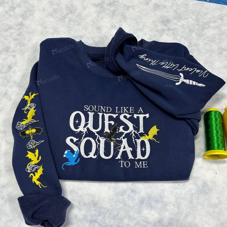May include: A navy blue long-sleeved sweatshirt with the text "SOUND LIKE A QUEST SQUAD TO ME" embroidered in white. The sweatshirt has yellow and blue dragon designs embroidered on the sleeves.