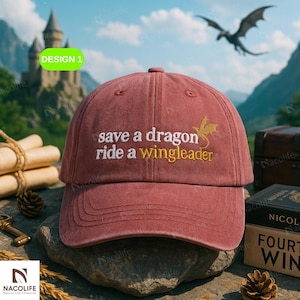May include: A maroon baseball cap with the text "save a dragon ride a wingleader" embroidered in white and gold. The cap has a curved peak and a classic six-panel design. The background includes a castle, a dragon, and a treasure chest.