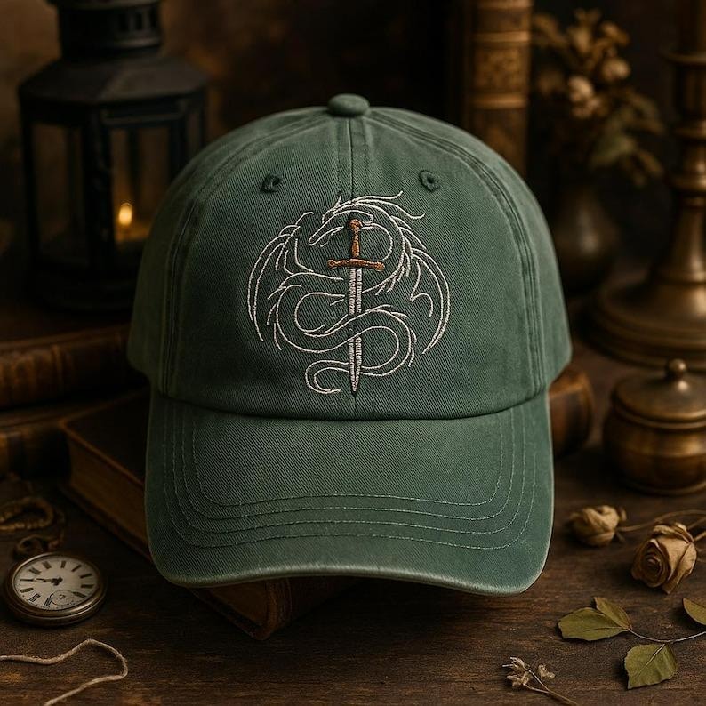May include: A green baseball cap with a white embroidered design of a dragon wrapped around a sword. The cap has a curved brim and a fabric strap closure.
