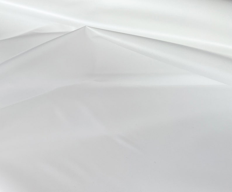 May include: White fabric with smooth texture and subtle wrinkles, creating a soft, flowing effect.