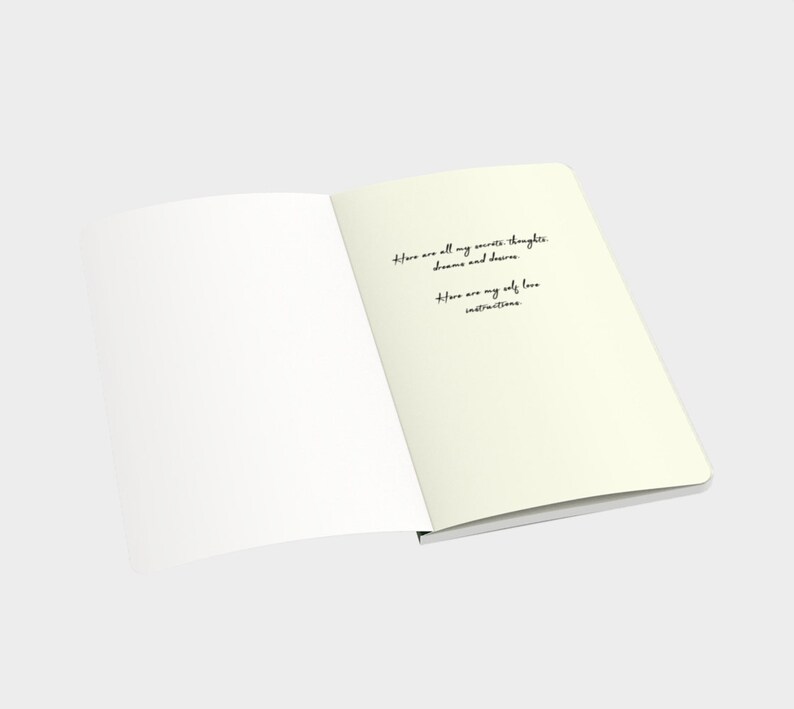 May include: An open notebook with blank pages on the left and a handwritten message on the right page. The message reads: "Here are all my secrets, thoughts, dreams and desires. Here are my self love instructions."