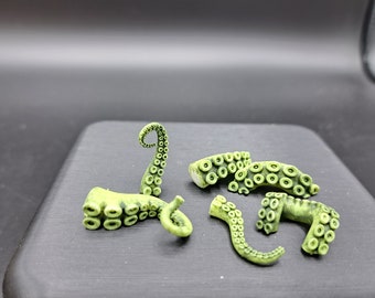 May include: A set of six green plastic octopus tentacles, each with a different pose and shape. The tentacles are detailed with suction cups and are perfect for adding a touch of whimsy to any craft project.