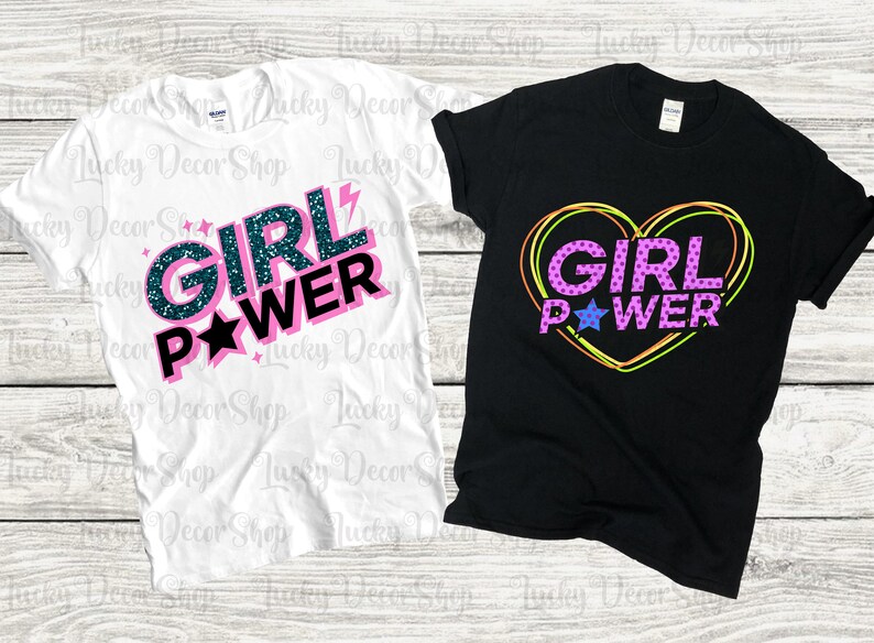 May include: Two t-shirts with the phrase "Girl Power" in different styles. One shirt is white with pink and blue glitter lettering and a star. The other shirt is black with the phrase in a pink heart with a blue star.