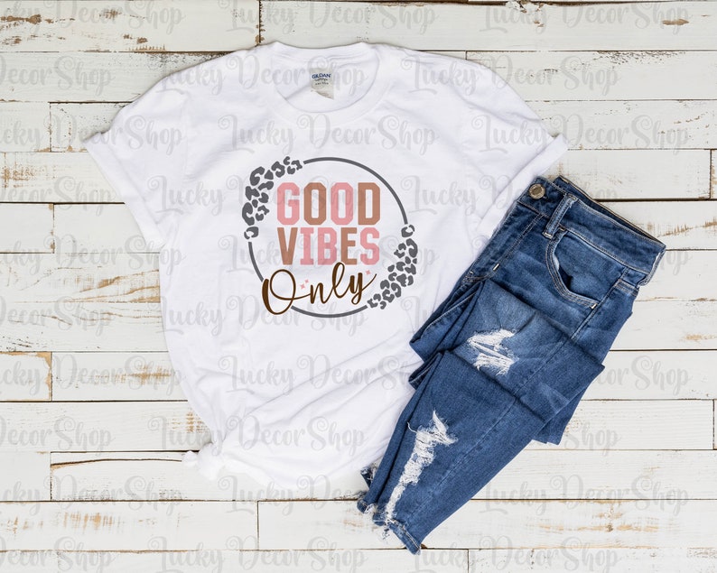 May include: White t-shirt with a gray circle and the text "GOOD VIBES ONLY" in pink and brown letters. The circle is surrounded by a leopard print design.