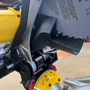 May include: Close-up of a yellow and gray miter saw with a black blade guard. The saw is set at a 45-degree angle and has a dust collection port. The blade is labeled "ATB 85 095 Kert 069 Plate 27.1".
