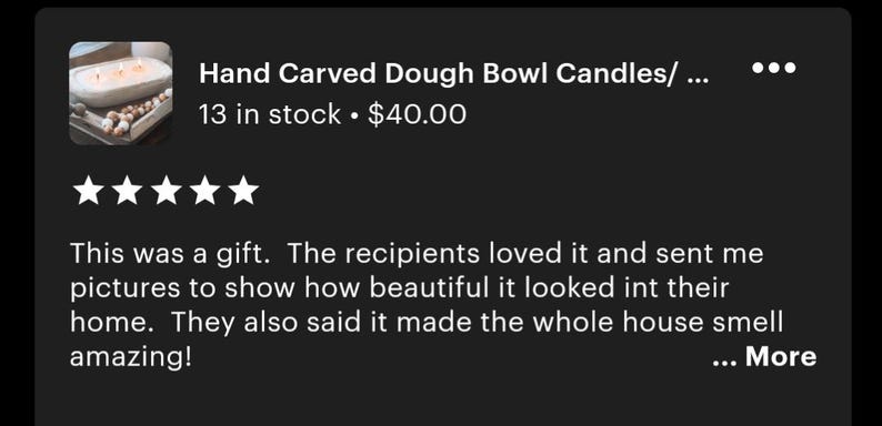 May include: A hand-carved wooden dough bowl candle featuring three lit wicks, positioned on a tray with a string of wooden beads. The text "Hand Carved Dough Bowl Candles" is visible, along with a five-star rating and a customer review about a gift.
