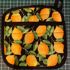 May include: Black pot holder with a lemon print. The pot holder has a black border and a loop handle.