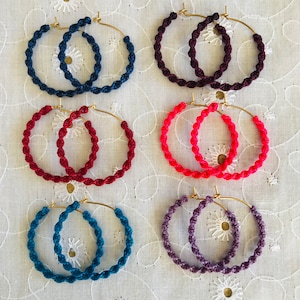 Peut inclure: Six paires de boucles d'oreilles créoles en cordon torsadé. Les créoles sont de différentes couleurs, notamment rouge, bleu, violet et rose.