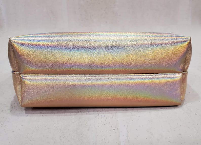 May include: A white ceramic mug with a black handle and the text "But First, Coffee" in a bold, black font. The mug is filled with a dark liquid, likely coffee, and sits on a light-colored surface.