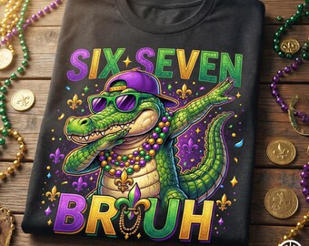 May include: Black t-shirt with a colorful graphic of an alligator wearing sunglasses and a purple hat, dabbing. The text on the shirt reads "SIX SEVEN BROUH" in purple and green. Mardi Gras beads and coins surround the shirt.