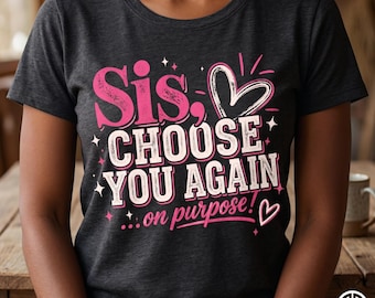 May include: Dark gray t-shirt with the text "Sis, CHOOSE YOU AGAIN ...on purpose!" in pink and white. The design includes a heart and starburst accents, creating a playful and loving message.