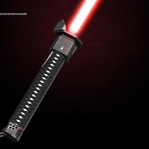 Puede incluir: Un sable de luz negro con una hoja roja y un mango estilo katana. El mango tiene un agarre con un patr&oacute;n blanco y negro.