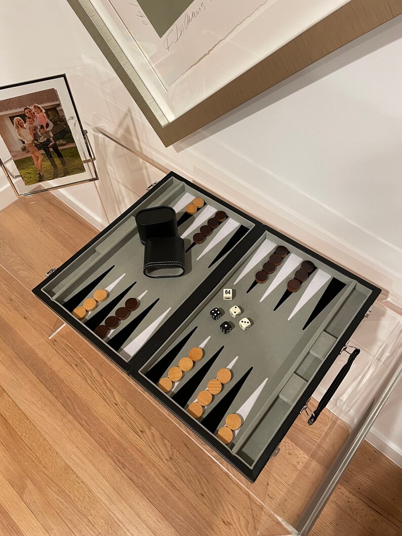 May include: A black backgammon set with a gray felt playing surface, wooden playing pieces, and dice. The set is open and ready to play.