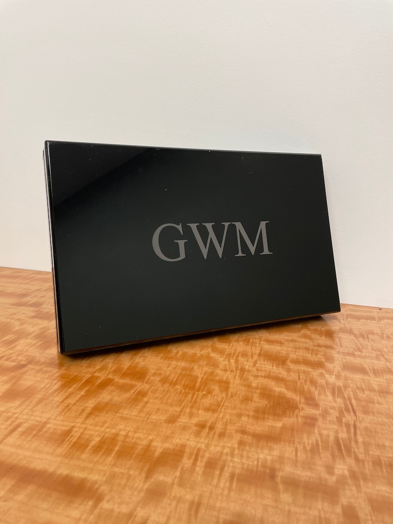 May include: A black rectangular box with the initials "GWM" engraved in silver lettering.
