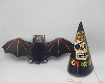 May include: A black Halloween bat decoration with orange accents and a black party hat with a skull graphic and the words "Trick or Treat". The hat has a string attached.