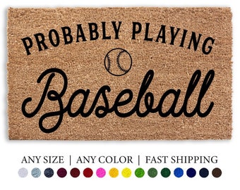 Może przedstawiać: Brązowa mata kokosowa z napisem "Probably Playing Baseball" czarnymi literami. W tekście znajduje się grafika przedstawiająca piłkę baseballową. Mata ma białą ramkę, a pod głównym tekstem znajduje się napis "Any Size | Any Color | Fast Shipping".