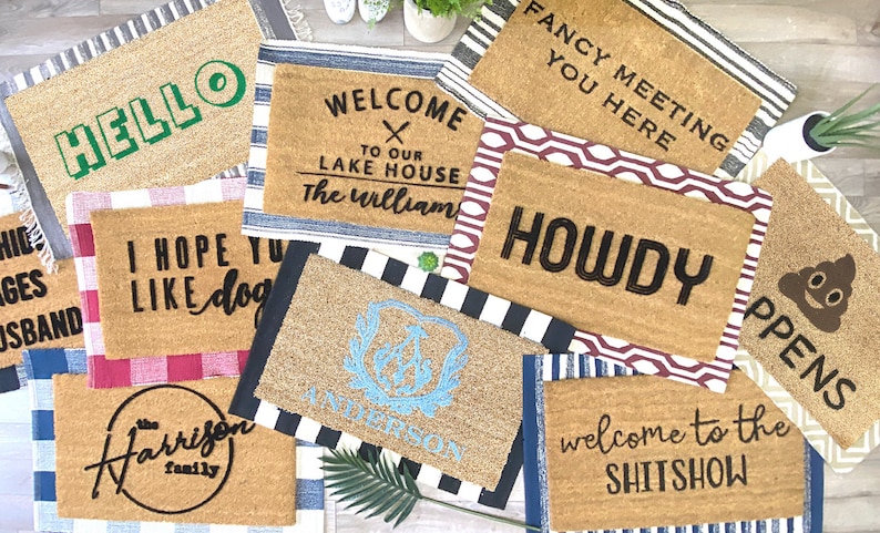 May include: A collection of ten doormats with various welcome messages and designs. The doormats are made of coir and have a variety of colors and patterns. Some of the messages include "Hello", "Welcome to our Lake House", "Fancy Meeting You Here", "Howdy", "I Hope You Like Dogs", "The Harrison Family", "Welcome to the Shit Show", and "PPENS".