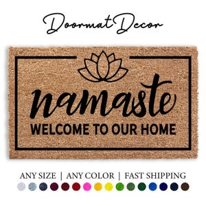 May include: A brown coir doormat with black text that reads "namaste WELCOME TO OUR HOME". A black lotus flower design is above the text.