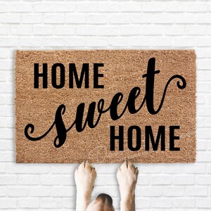 May include: A brown coir doormat with the text "Home sweet home" in black lettering.