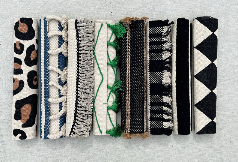 May include: Eight different patterned rugs with fringe, including leopard print, stripes, and geometric designs in black, white, and brown.