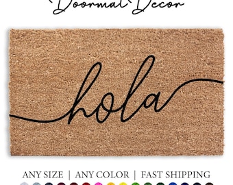 May include: A brown coir doormat with the word "hola" written in black cursive script. The doormat is available in various sizes and colors.