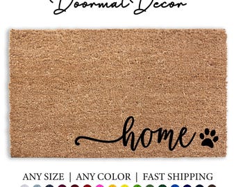 May include: A brown coir doormat with the word "home" in black cursive script and a black paw print. The text "Doormat Decor" is at the top of the image. The text "ANY SIZE | ANY COLOR | FAST SHIPPING" is at the bottom of the image. There are 15 color swatches below the text.