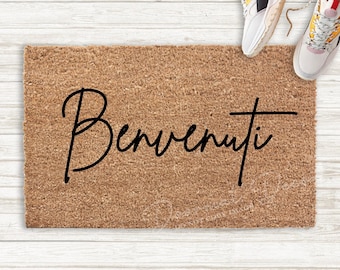 Op de afbeelding: Een bruine kokosmat met het woord "Benvenuti" in zwarte cursieve letters.