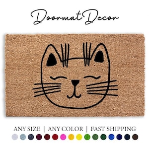 Pode incluir: Um tapete de coco castanho com um contorno preto de um rosto de gato. O gato tem os olhos fechados e uma boca sorridente. O texto "Doormat Decor" está no topo da imagem. O texto "ANY SIZE | ANY COLOR | FAST SHIPPING" está na parte inferior da imagem.