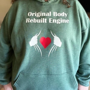 May include: Green hooded sweatshirt with the text "Original Body Rebuilt Engine" in white lettering and a red heart with white hands reaching out from the heart.