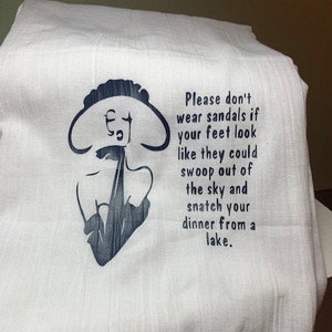 May include: White tea towel with a black and white illustration of a person with the text "Please don't wear sandals if your feet look like they could swoop out of the sky and snatch your dinner from a lake."