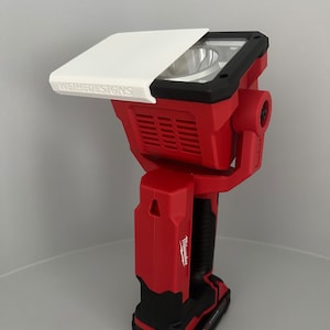 May include: A red and black Milwaukee work light with a white diffuser. The diffuser has the text "WEIHEDESIGNS" printed on it.