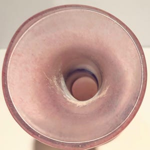 Puede incluir: El interior de un jarr&oacute;n de vidrio rosa con una abertura ancha. El jarr&oacute;n tiene un acabado liso y brillante.