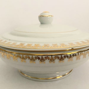 May include: White porcelain serving bowl with a lid, featuring a gold trim and intricate floral pattern.