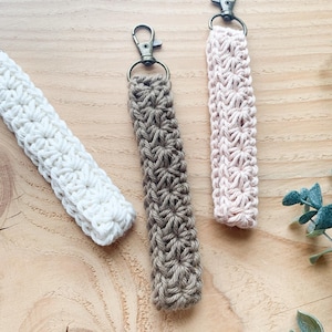 May include: Three crocheted keychains with metal key rings. The keychains are brown, pink, and white.