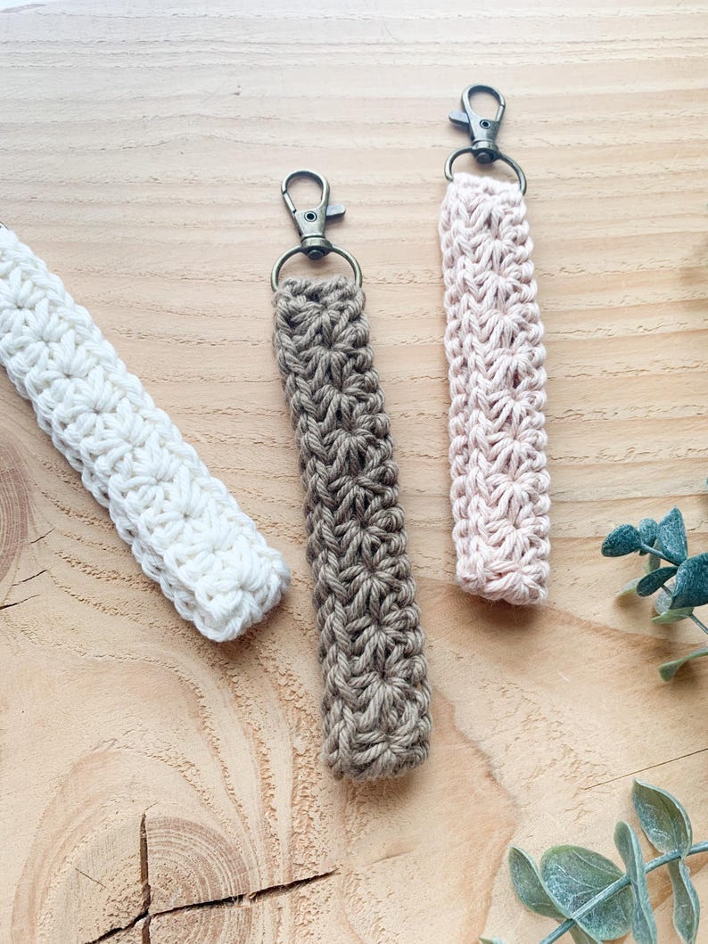May include: Three crocheted keychains with metal key rings. The keychains are brown, pink, and white.