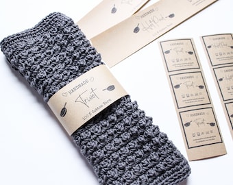 Puede incluir: Un posavasos de crochet gris con una etiqueta de papel marrón que dice "Handmade Trivet 100% Cotton Yarn".