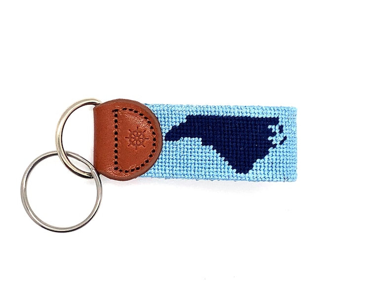 Peut inclure: Un porte-cl&eacute;s bleu et bleu marine avec une boucle en cuir orn&eacute;e d'une boussole. Le porte-cl&eacute;s est tiss&eacute; avec le contour de l'&eacute;tat de Caroline du Nord.